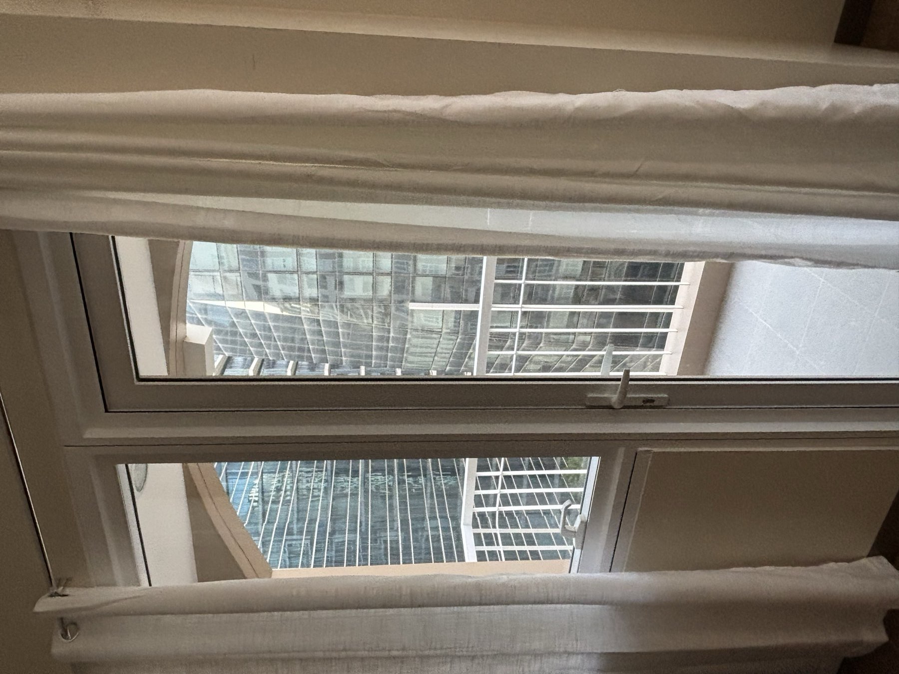 Balcony door framed by white curtains, opening onto a private balcony with tower views over the Mactan Newtown township